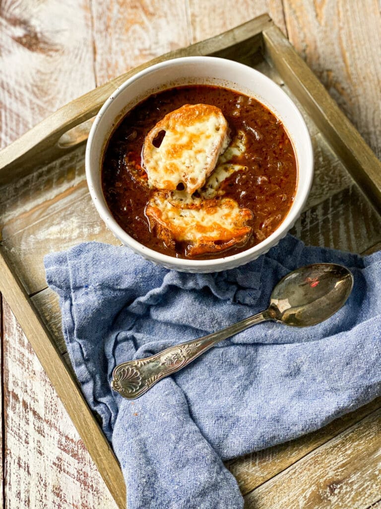 onion soup in a bowl with a cheese covered piece of toast and a blue napkin