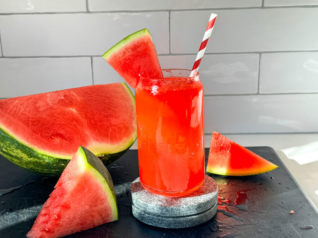 watermelon mocktail with a straw and wedges of watermelon
