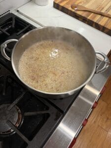 Arborio rice and shallots and broth in a pan