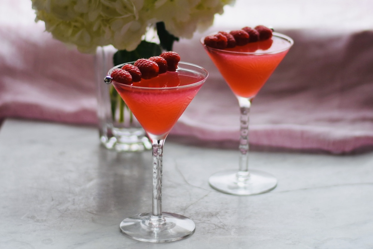 2 raspberry martinis with a vase of hydreangeas
