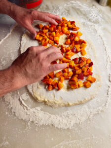 peaches going onto peach cobbler roll dough