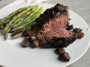 filet mignon medium rare steak on a plate with asparagus and mushrooms