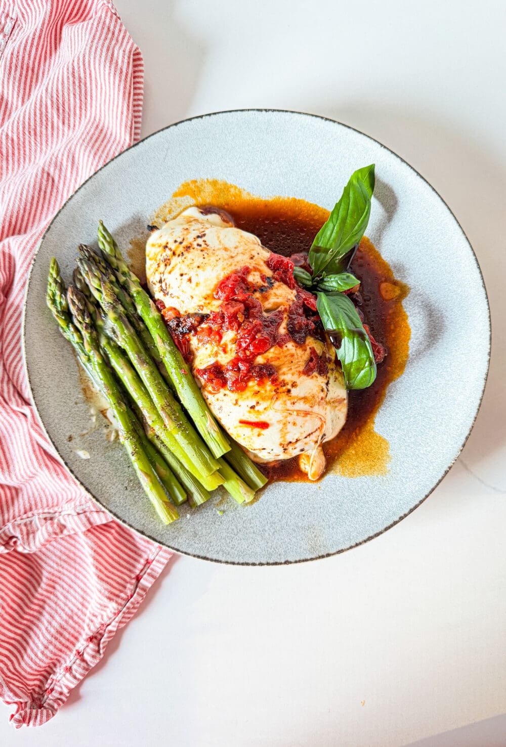 Caprese chicken on a plate with asparagus
