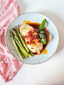 Caprese chicken on a plate with asparagus