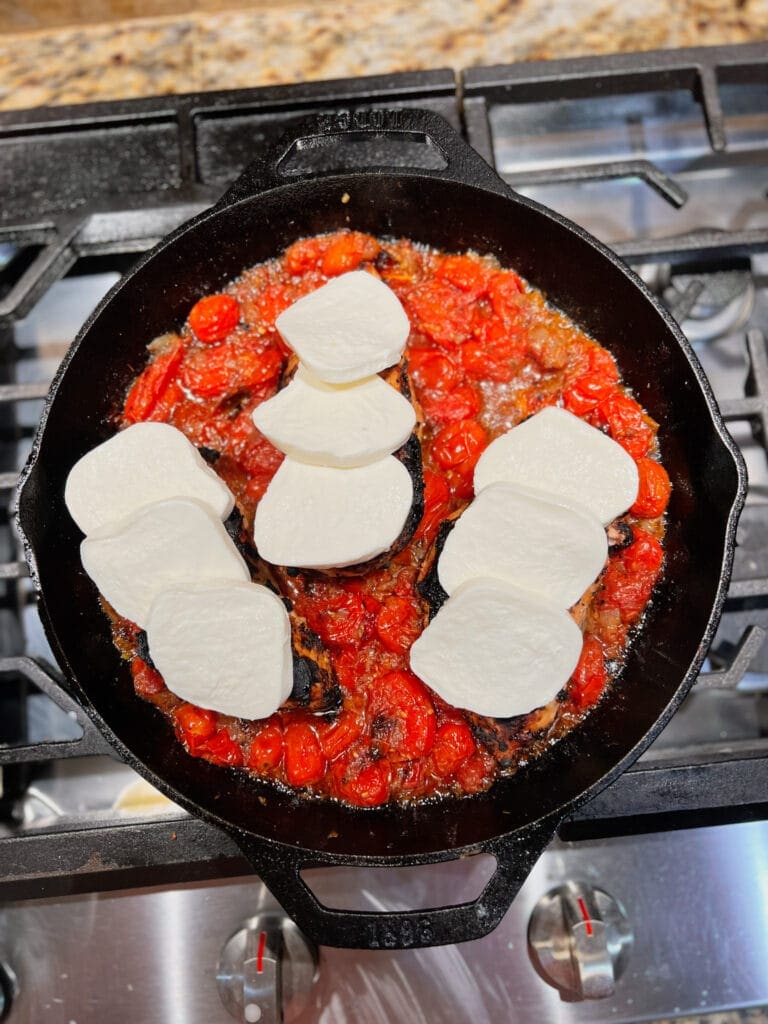 fresh mozzarella layered on chicken in a pan with tomato sauce