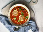 bowl of panera 10 vegetable soup with lemons and a blue napkin and spoon