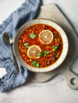 bowl of panera 10 vegetable soup with lemons and a blue napkin and spoon