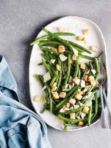 ensalada de ejote recipe-green bean caesar salad on a dish with a blue napkin