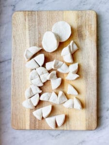 refrigerated biscuits quartered on a cutting board
