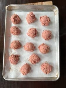 Ground turkey burgers not flattened yet on parchment on cookie sheet