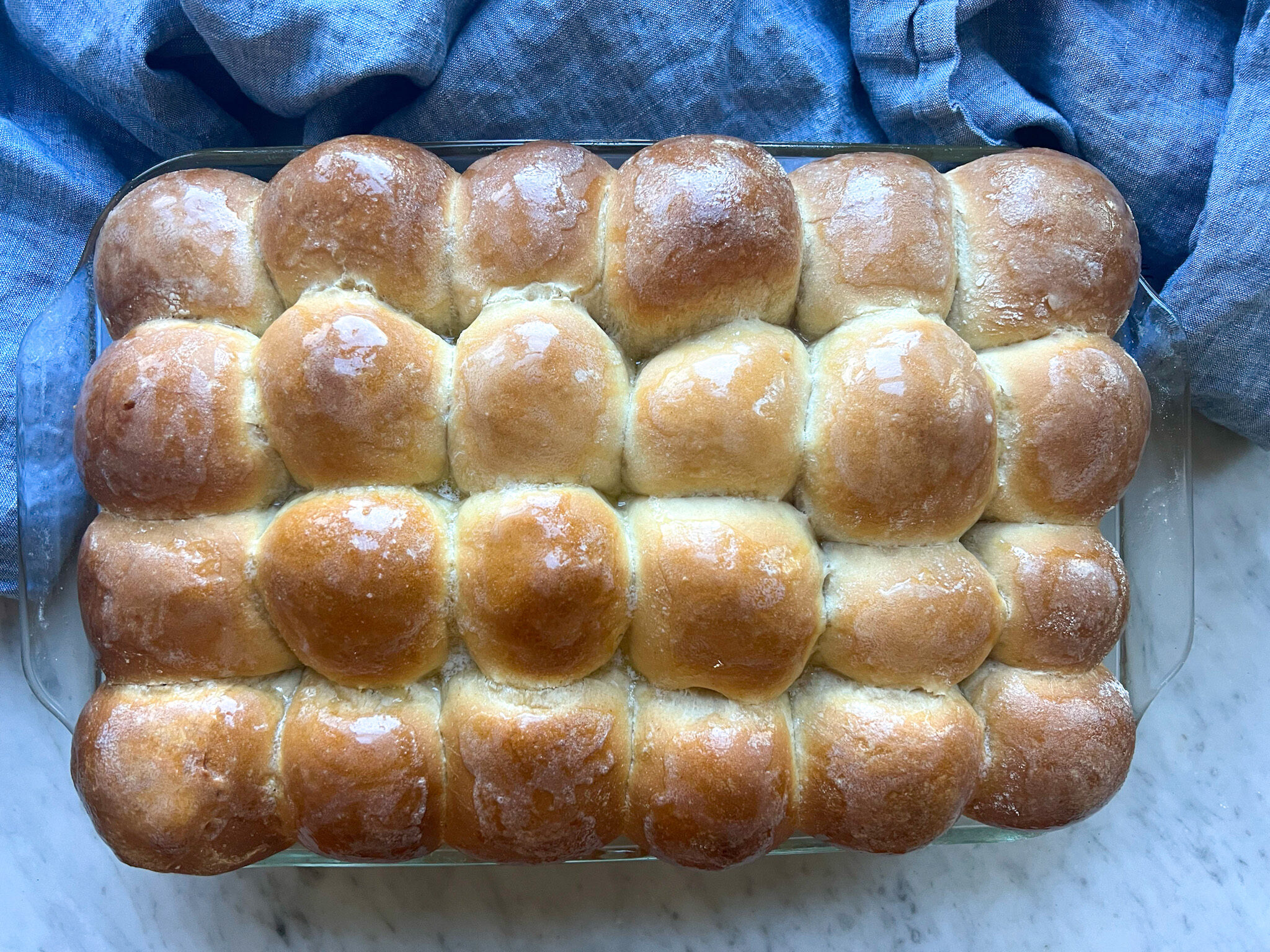 baked rolls with butter over the top and a blue towel