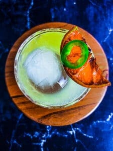 skinny spicy margarita with dried citrus wedge and jalapeño on top