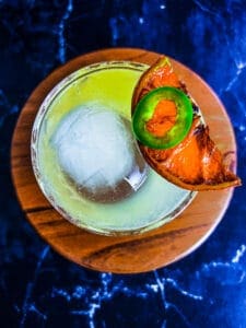 skinny spicy margarita with dried citrus wedge and jalapeño on top