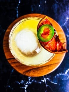 skinny spicy margarita with dried citrus wedge and jalapeño on top