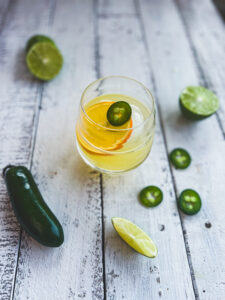 skinny spicy margarita with dried citrus wedge and jalapeño on top