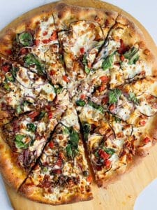 a whole pizza with lots of ingredients and pizza seasoning on top