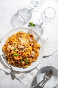 A plate of Marry Me Chicken Pasta and wine glass