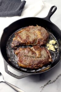 pan seared ribeye with garlic butter in a cast iron pan