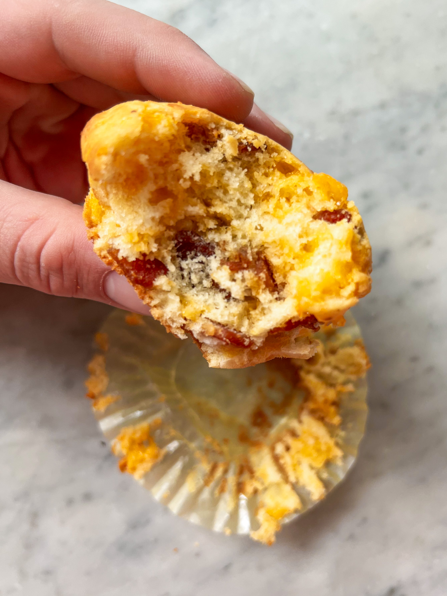 bacon cheese muffin with a bite out being held with a hand