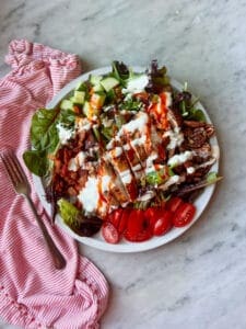 smoked grilled chicken thigh salad with ranch and buffalo sauce on top