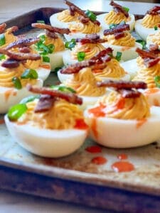 Smoked Deviled Eggs with Smoked Bacon Candy and Green onions and hot sauce