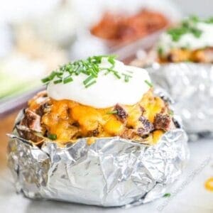 Leftover steak baked potato in foil with cheese and steak on top
