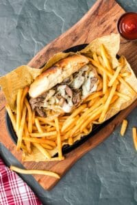 philly cheese steak sandwich in a basket with french fries