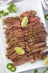 Flank steak on platter with limes