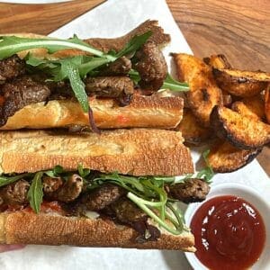 ribeye steak sandwich with potato wedges and ketchup
