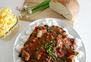Hearty steak and black bean chili on rice with bread