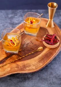 2 hot honey old fashioned on a platter with chilis and a spoon