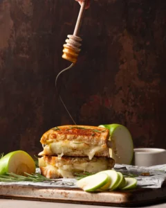 apple and brie grilled cheese with honey getting drizzled on top