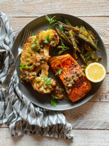 Cauliflower, okra and blackened salmon on a plate with a half of lemon