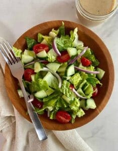 house salad in a bowl with lettuce, cucumbers tomatoes and a fork