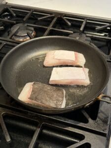 3 pieces of halibut in a pan on the stove