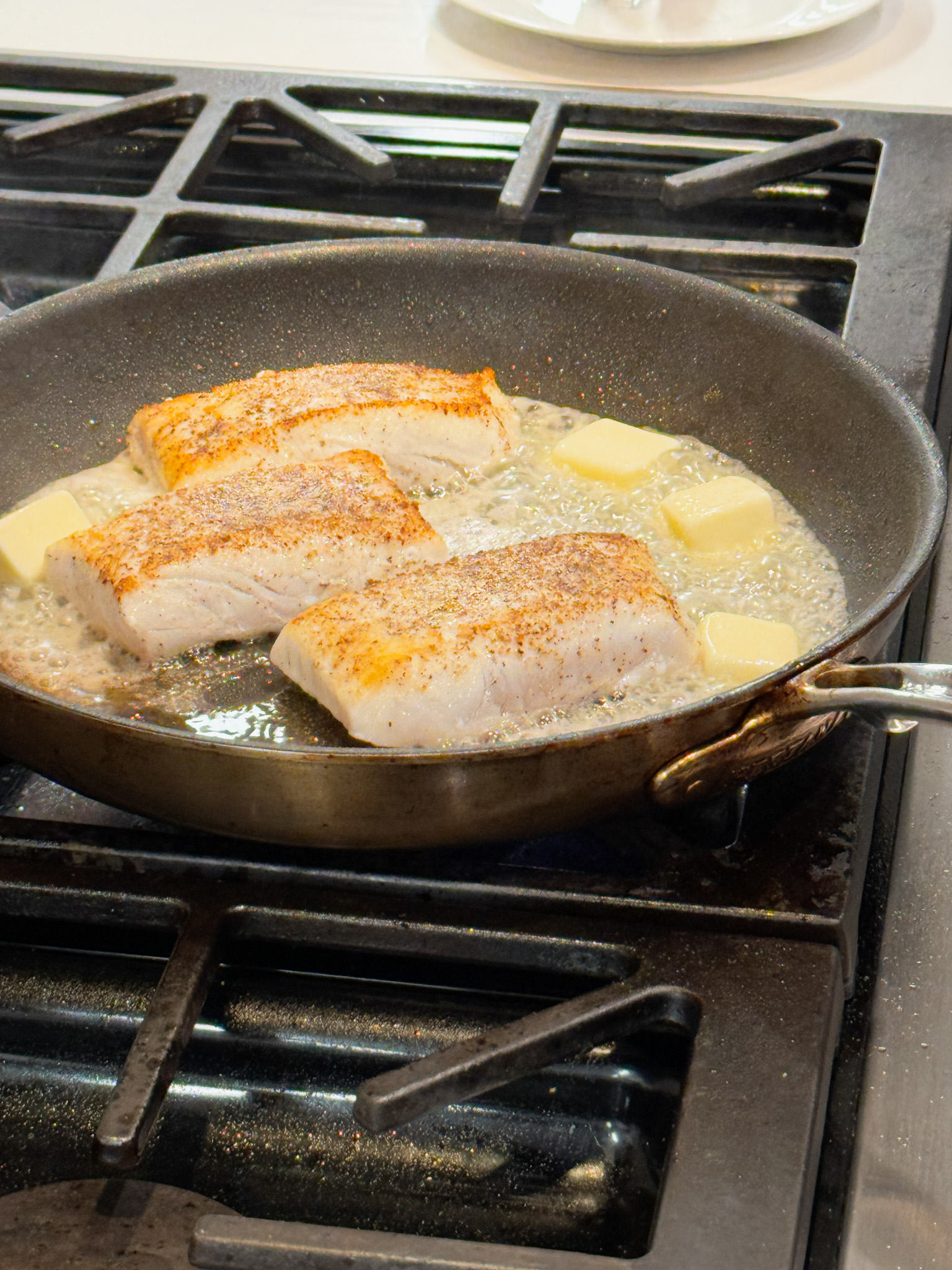 3 pieces of halibut in a pan with butter