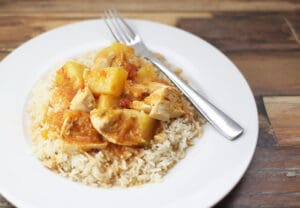 Mango chicken on rice on a white plate with a fork