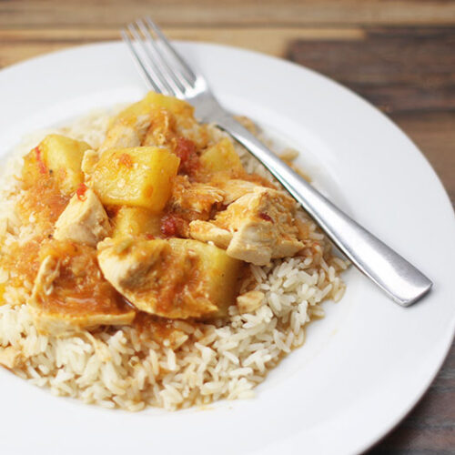 Mango chicken on rice on a white plate with a fork