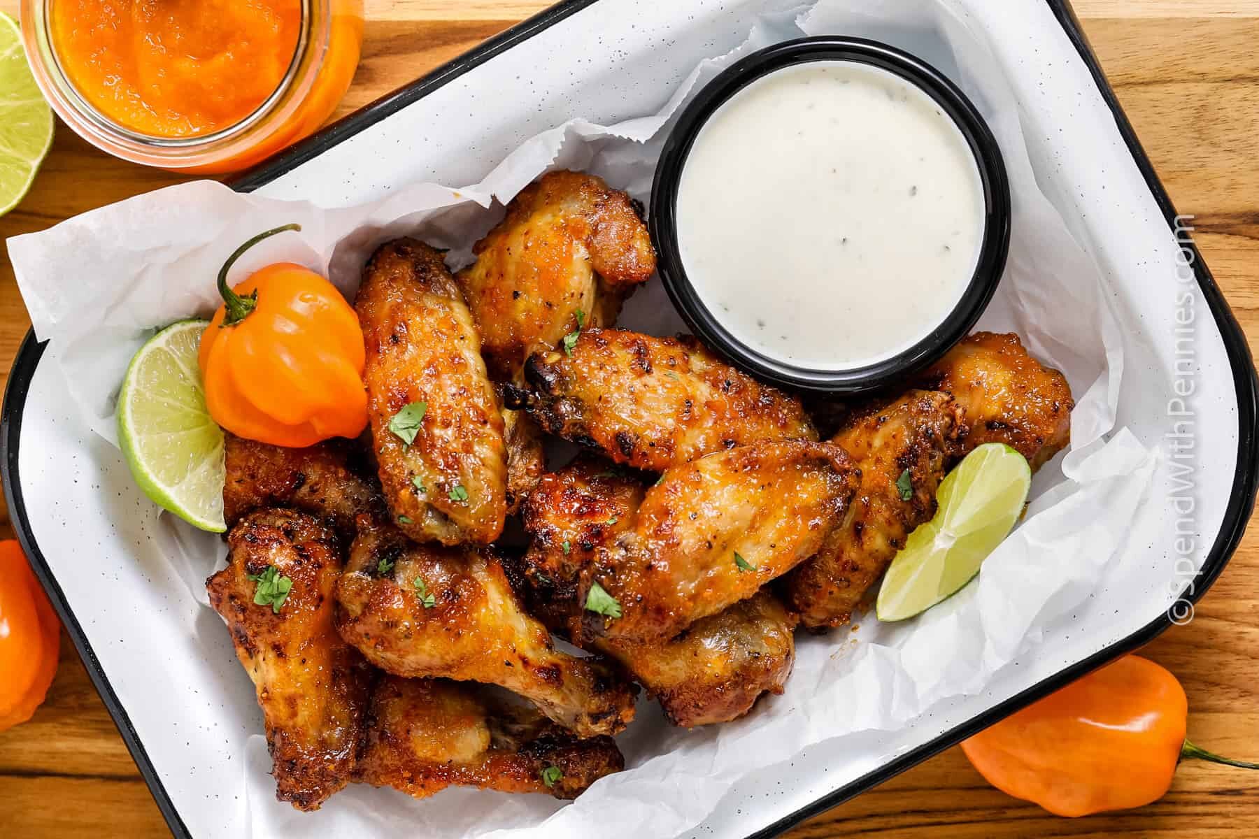 mango habanero wings with pepper and lime and ranch in a white and blue pan