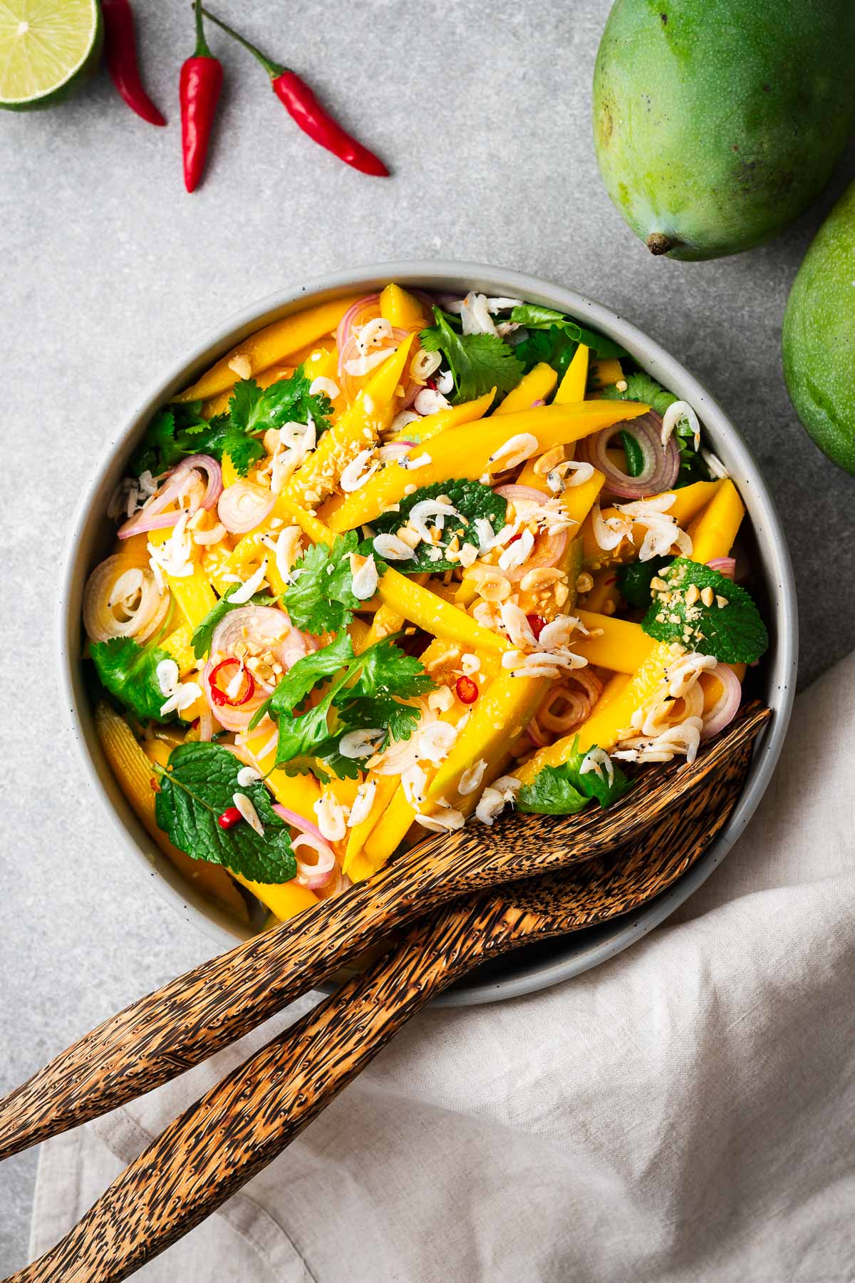spicy thai green mango salad on a plate with wooden serving forks