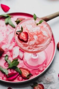 Strawberry white wine spritzer in a martini glass with strawberries