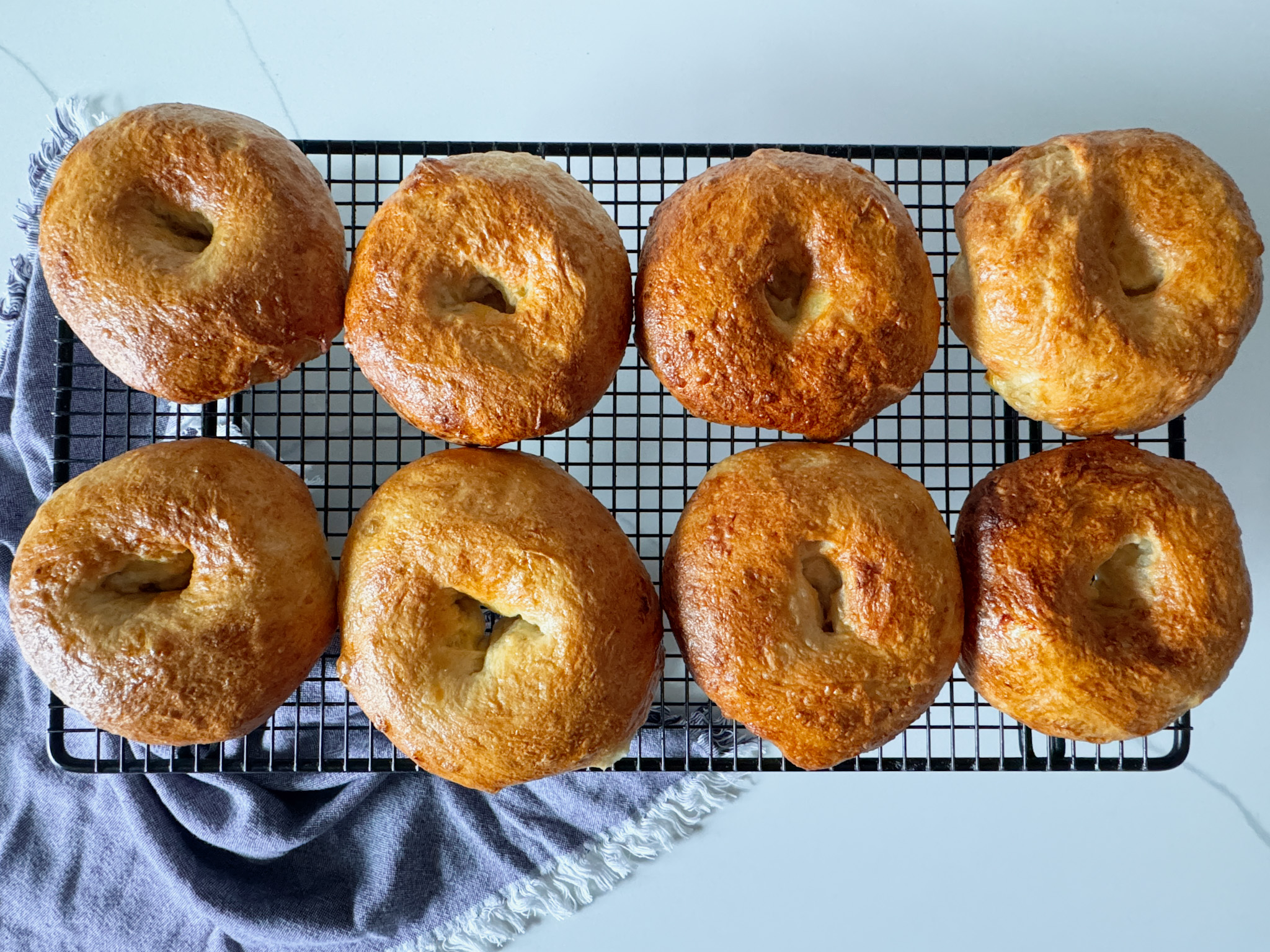 6 bagels on a cooling rack with a frayed blue napkin