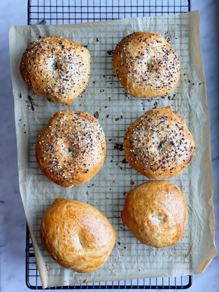 bagels cooling on parchment on a wire cooling wrack