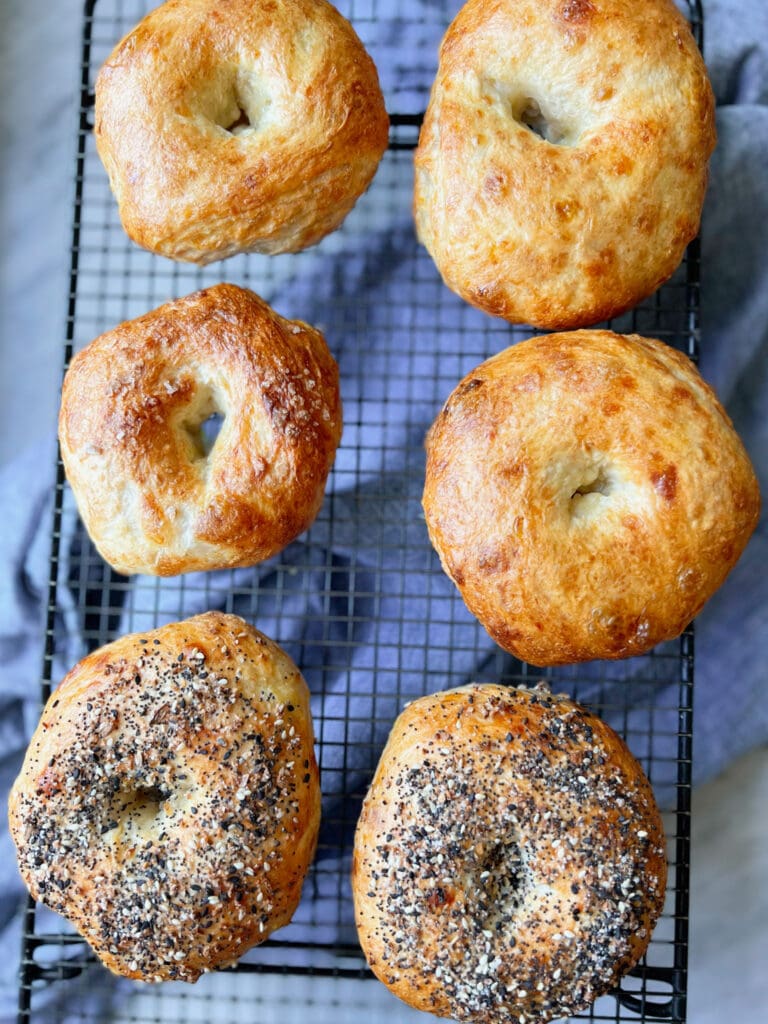 6 bagels on a cooling rack with a blue napkin.