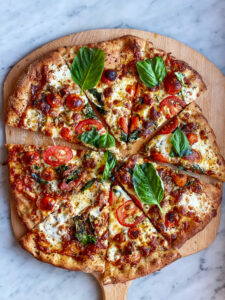 Pizza sliced and on a peel made with Trader Joe's pizza dough