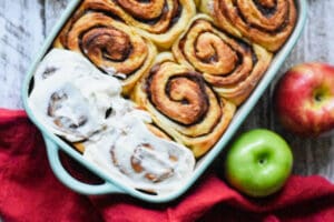 apple cinnamon rolls with cream cheese frosting and a green apple and a red naplkin