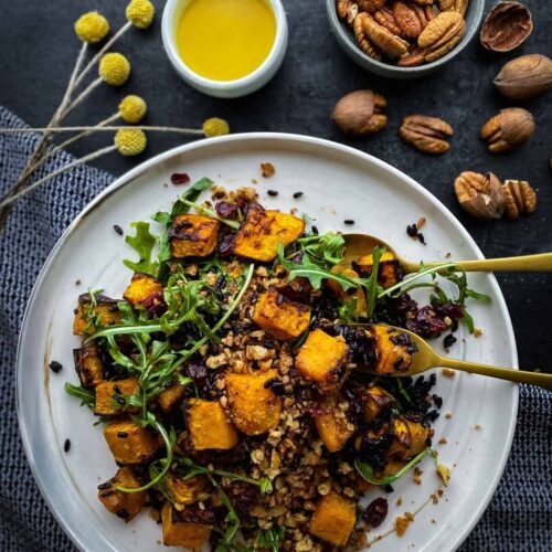 Vegan butternut squash salad on a white plate with dressing