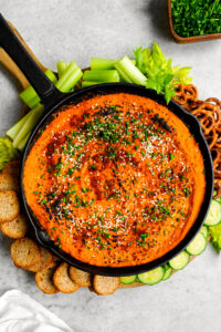 butternut squash dip in a cast iron pan with veggies and pretzels and bread