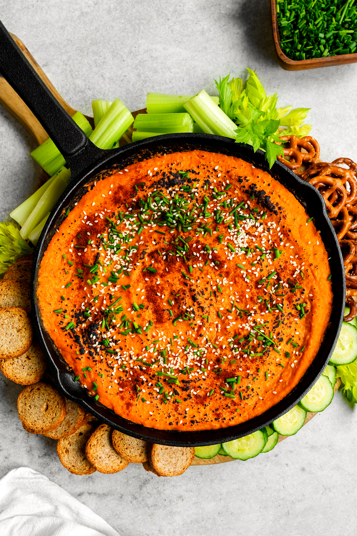 butternut squash dip in a cast iron pan with veggies and pretzels and bread