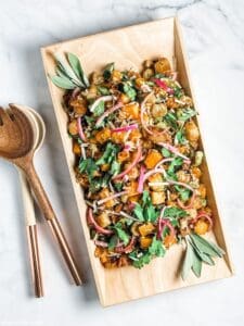 squash panzanella salad in a rectangle dish with salad servers